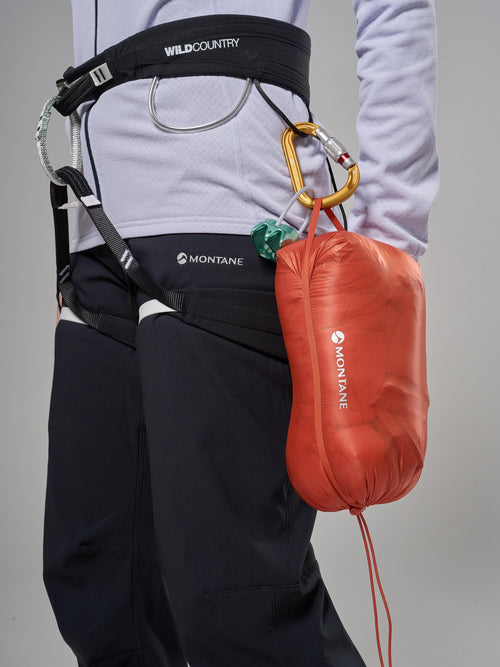Person wearing a climbing harness with a red Montane bag on a gray background