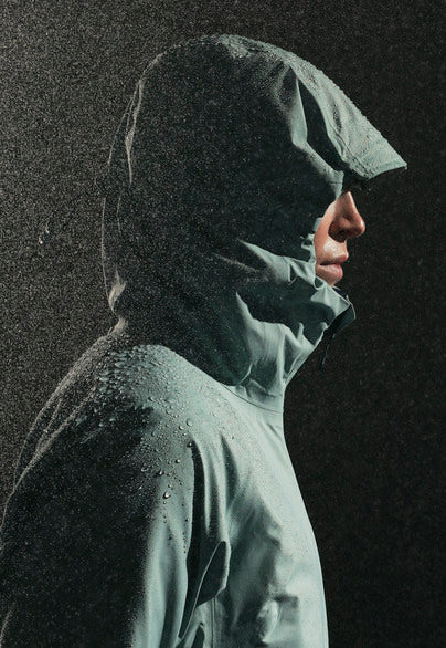 Model in waterproof jacket with hood up in rain